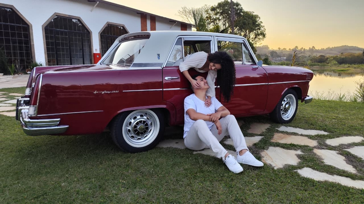 Casal junto ao carro clássico ao pôr do sol